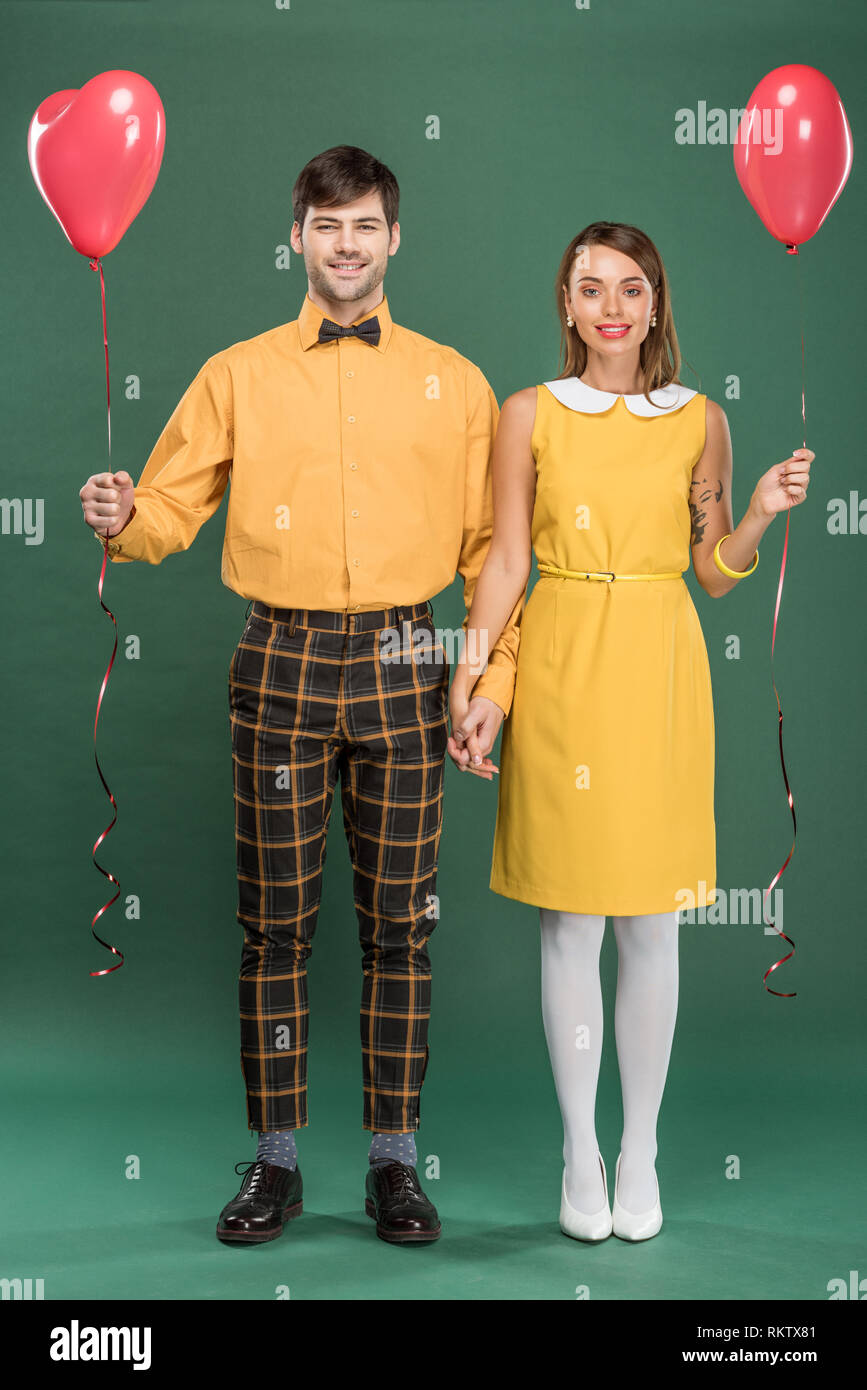 beautiful smiling couple holding hands and heart shaped balloons while ...