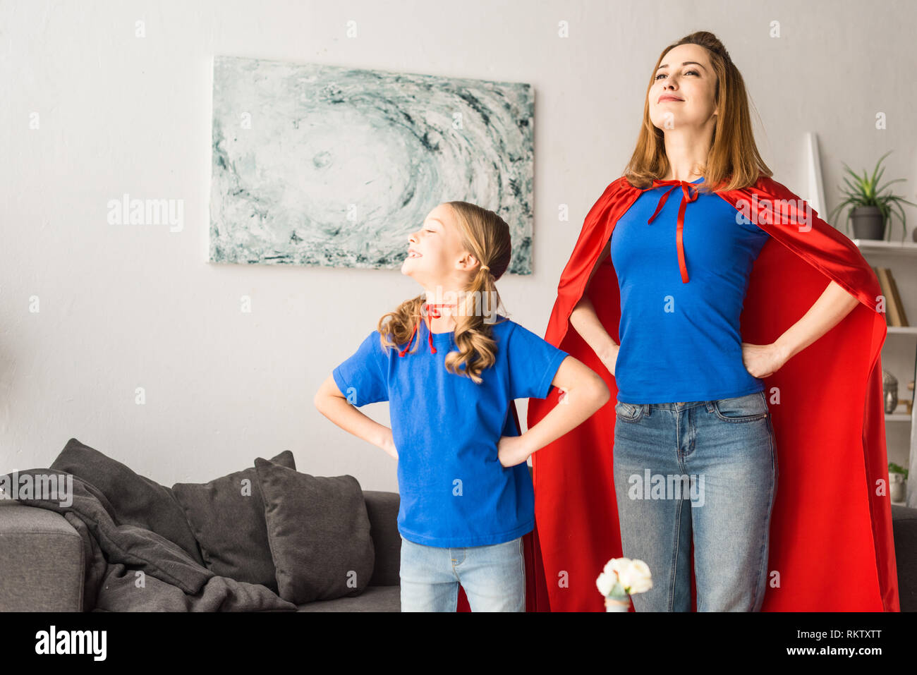 Mother and daughter in red cloaks looking away Stock Photo