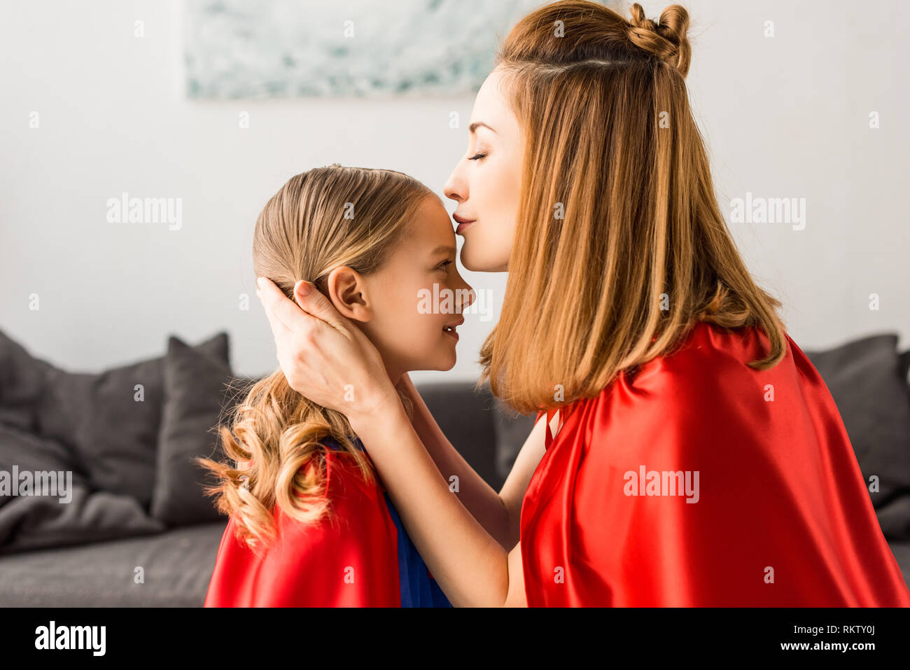 Beautiful mother kissing cute daughter at home Stock Photo