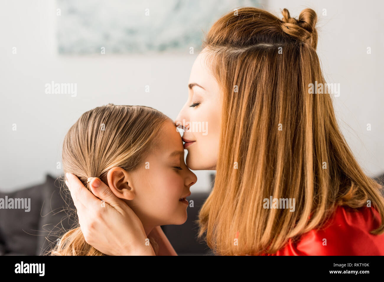 Close up of mother kissing daughter at home Stock Photo