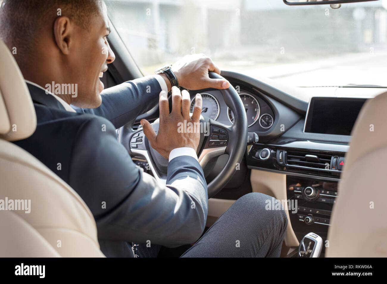 Young african american businessman driver sitting inside the car pushing  horn signaling to another vehicle smiling cheerful view from the back seat  Stock Photo - Alamy
