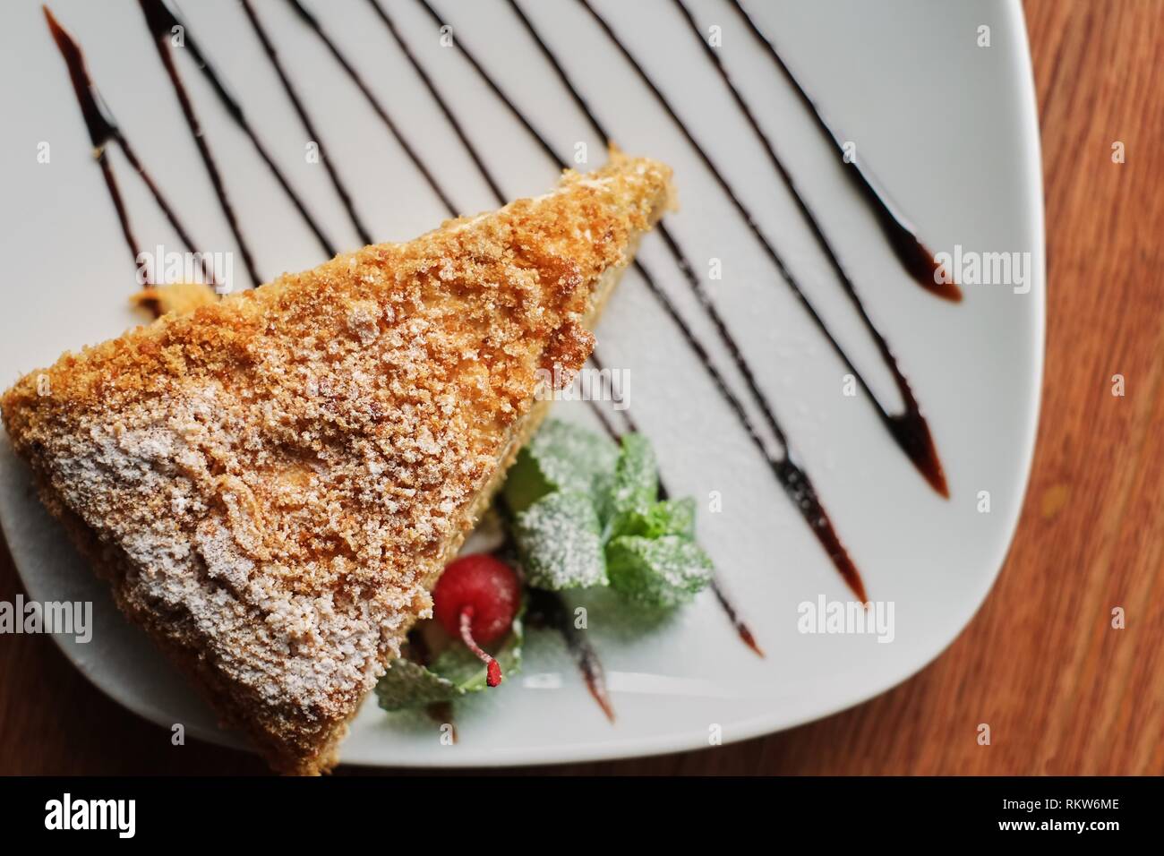 a piece of poured honey cake with chocolate topping on a plate, top view, set. Stock Photo