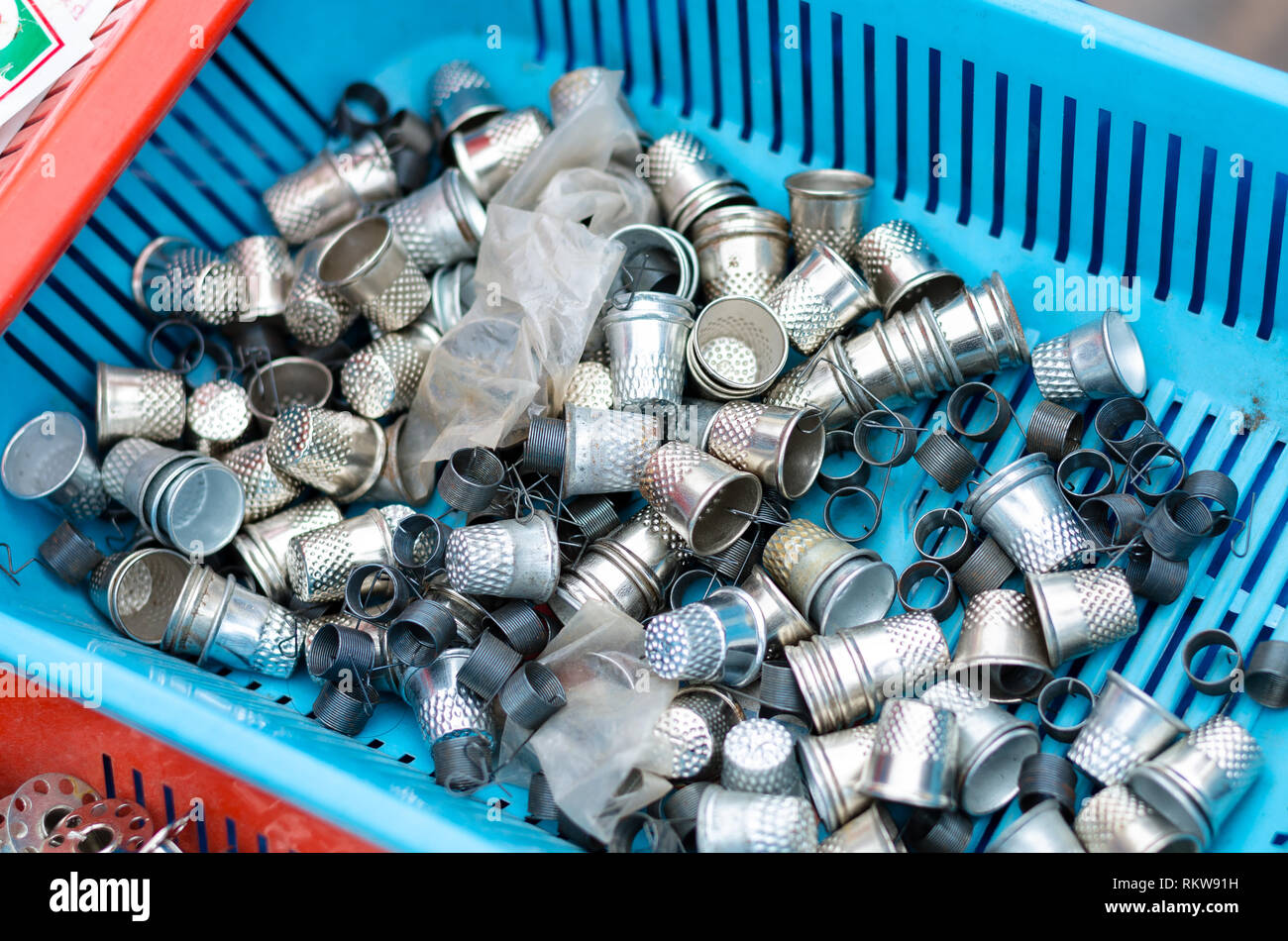 Silver metal thimbles in a blue basket. Stock Photo