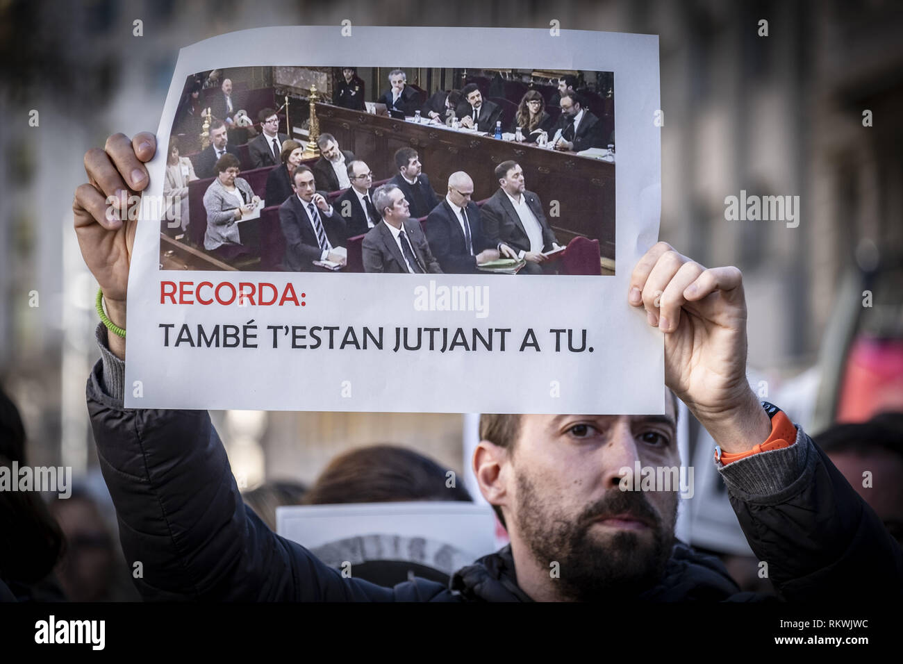 Barcelona, Catalonia, Spain. 12th Feb, 2019. A worker from the Department of Economy and Finance is seen during the protest showing an image taken from TV showing the first portrait image of the political prisoners since they were arrested.Hundreds of workers and officials of the General office of Catalonia have gone out to show their solidarity with political prisoners on their first day of trial. The workers of the Department of Economy have blocked the traffic of the Gran VÃ-a during the protest. Credit: Paco Freire/SOPA Images/ZUMA Wire/Alamy Live News Stock Photo