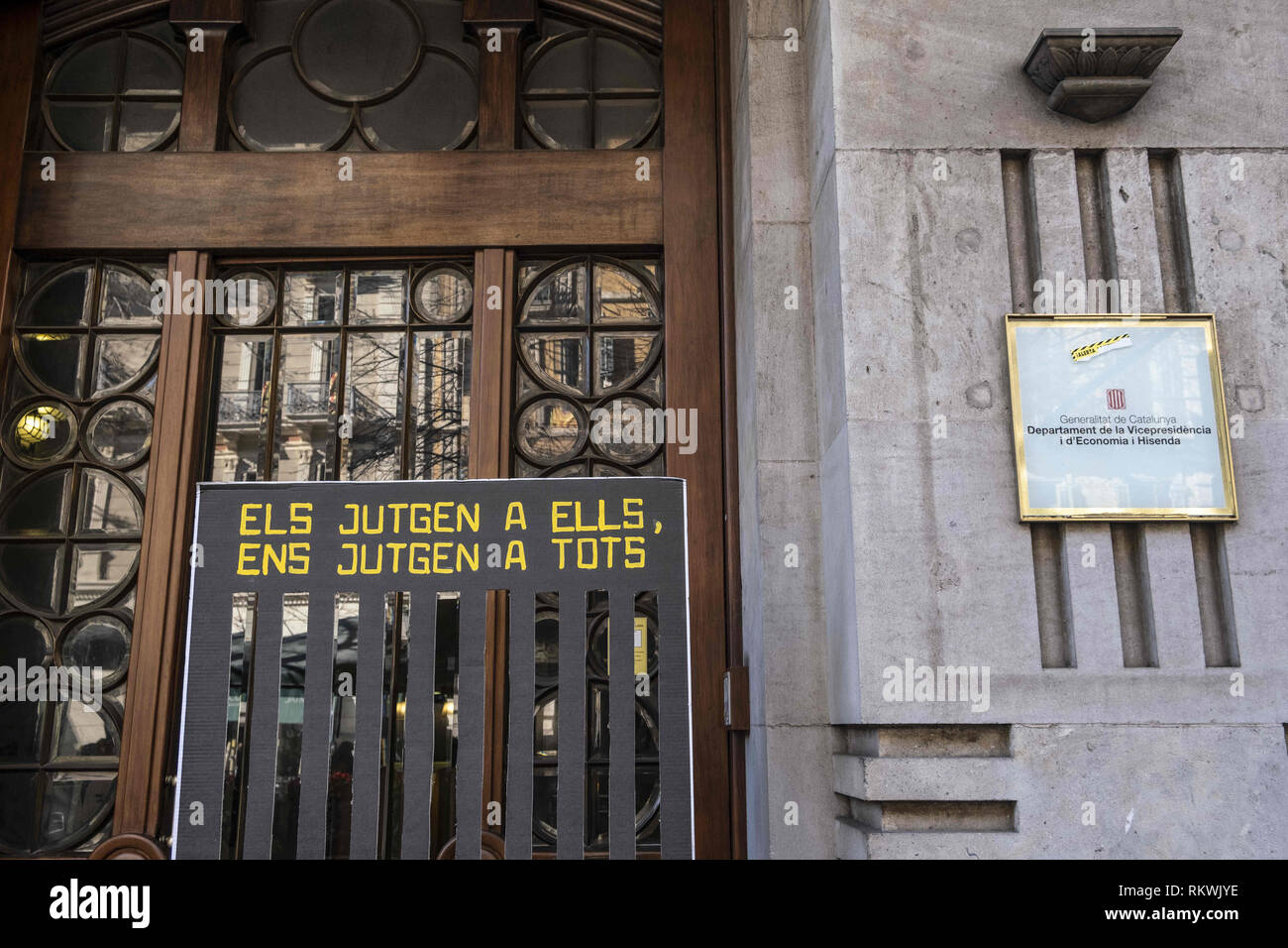 Barcelona, Catalonia, Spain. 12th Feb, 2019. A banner reads ''They judge them, they judge us all'' is seen at the door of the Department of Economy and Finance.Hundreds of workers and officials of the General office of Catalonia have gone out to show their solidarity with political prisoners on their first day of trial. The workers of the Department of Economy have blocked the traffic of the Gran VÃ-a during the protest. Credit: Paco Freire/SOPA Images/ZUMA Wire/Alamy Live News Stock Photo