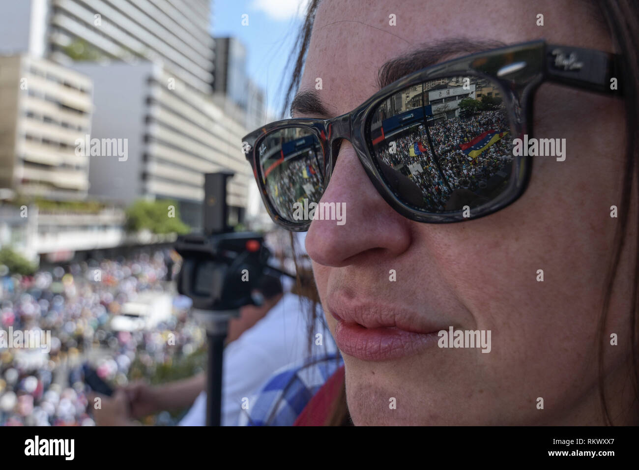 The crowd seen through the reflection of a woman sunglasses during a protest to call for a change in the government. Opponents gather at a protest organised by the PSUV (United Socialist Party of Venezuela) after the call from interim president Juan Guaido, to show their support to him, while asking the army to allow more humanitarian aids into the country. Stock Photo