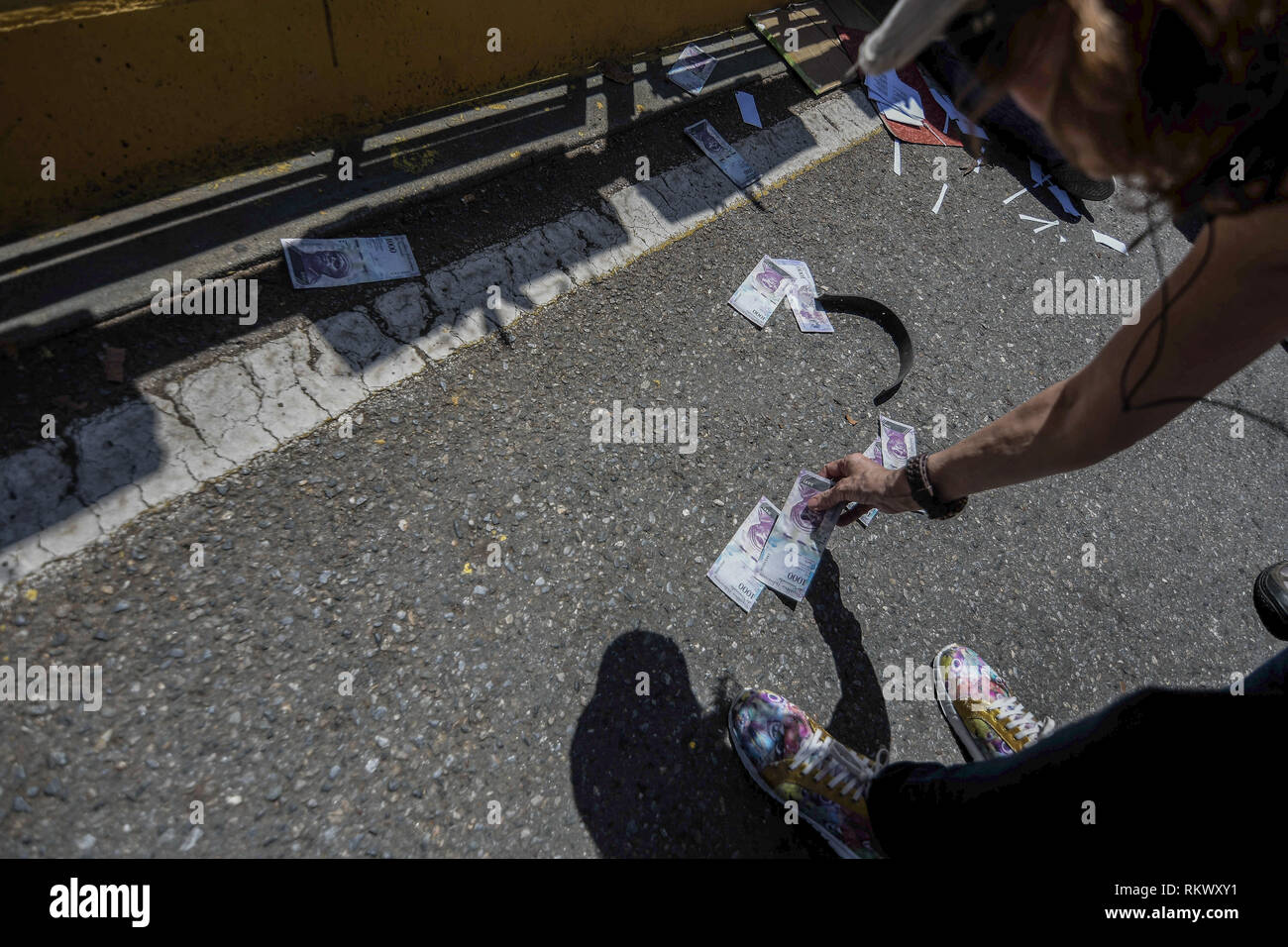 A woman seen picking up thrown banknote during a protest to call for a change in the government. Opponents gather at a protest organised by the PSUV (United Socialist Party of Venezuela) after the call from interim president Juan Guaido, to show their support to him, while asking the army to allow more humanitarian aids into the country. Stock Photo