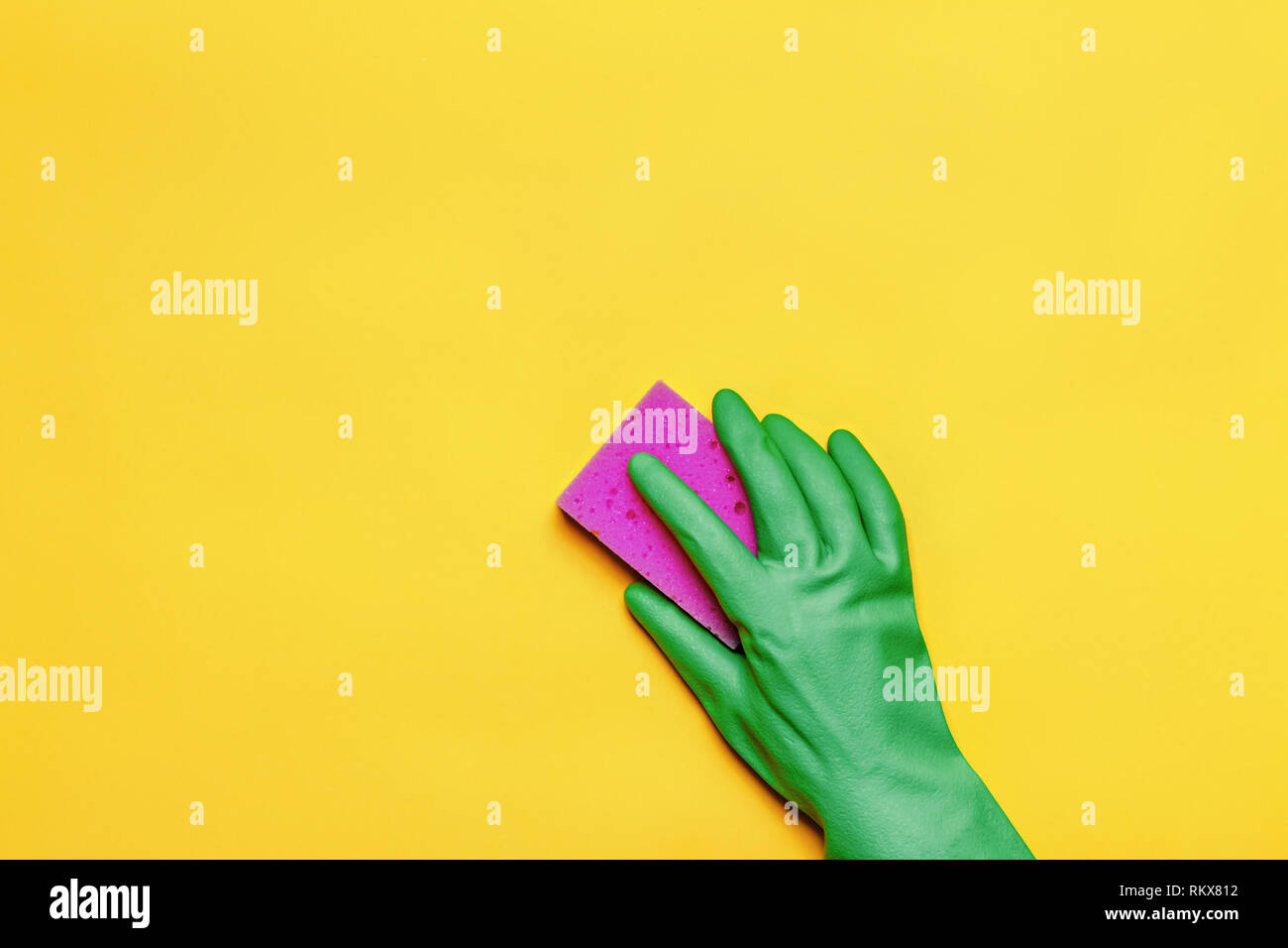 A hand in a rubber protective glove with a pink sponge on a yellow ...
