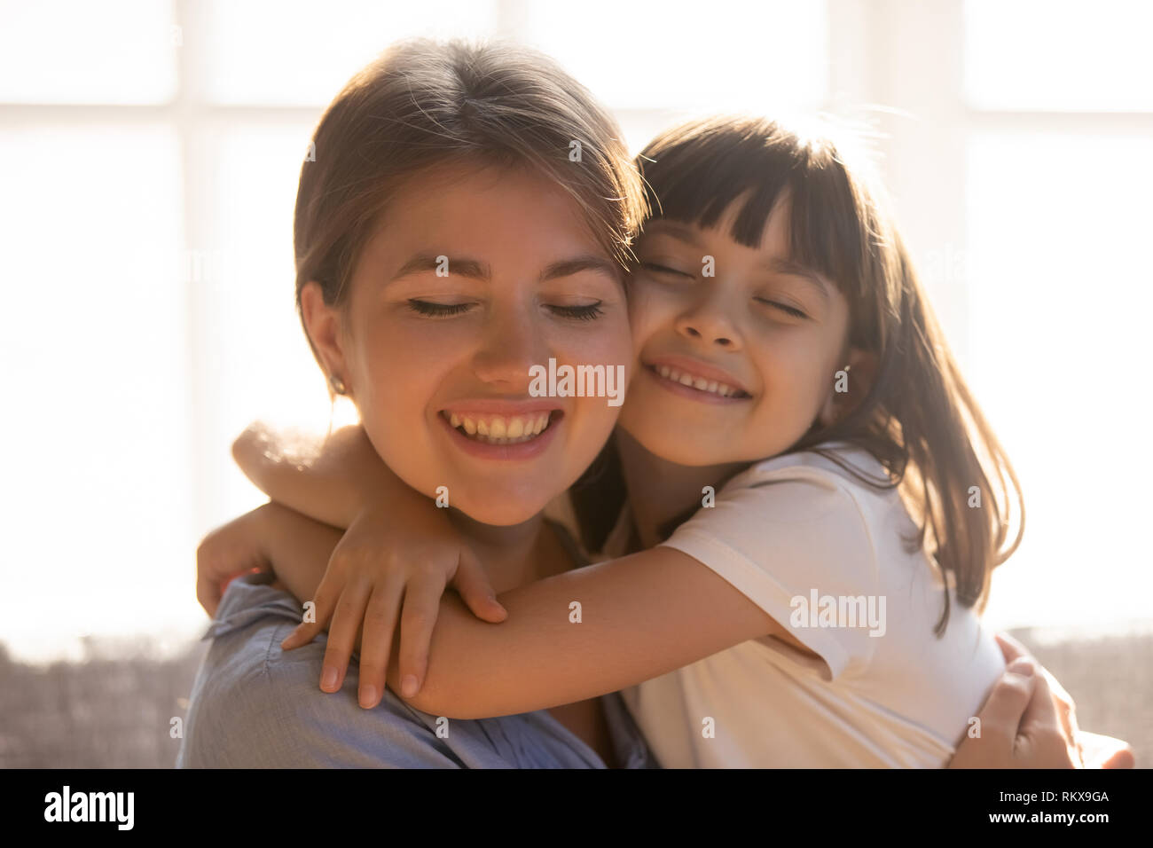 Loving affectionate little kid daughter hugging happy mom cuddling Stock Photo