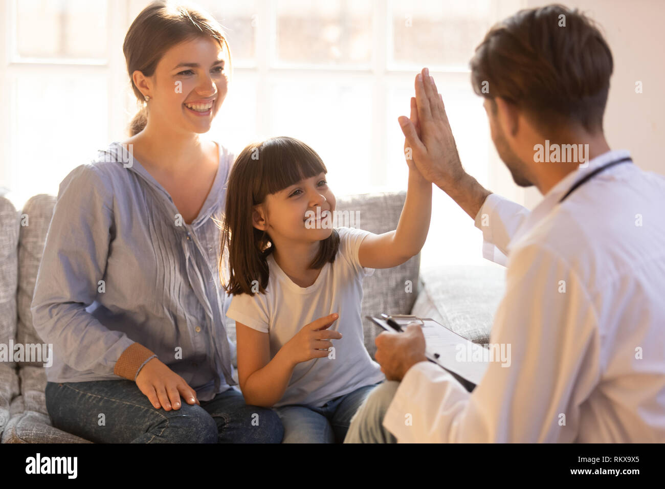 Happy cute child girl giving high five to male pediatrician Stock Photo
