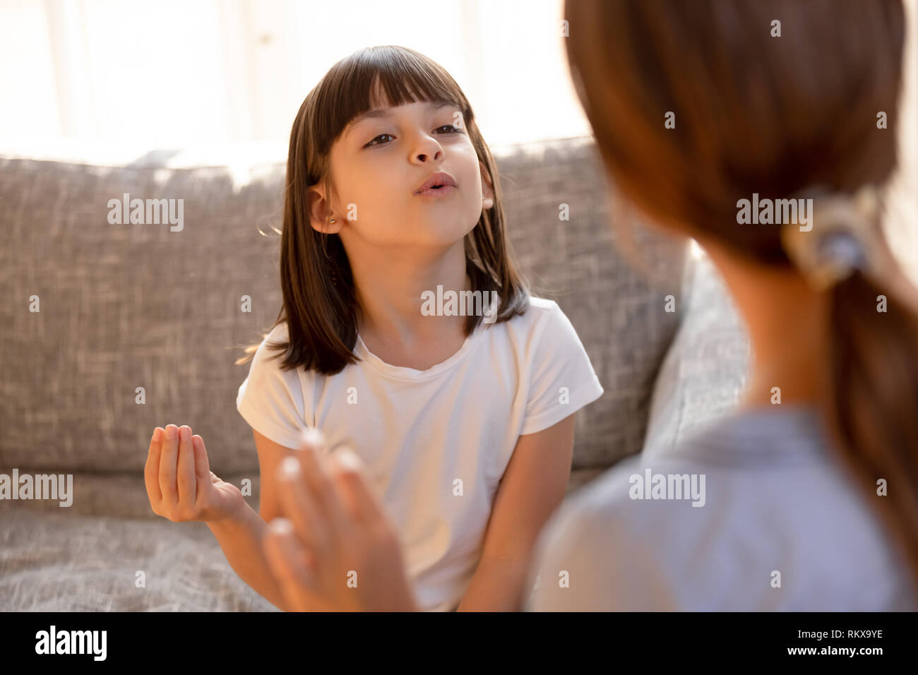 Cute stuttering child girl speaking doing exercises with speech therapist Stock Photo