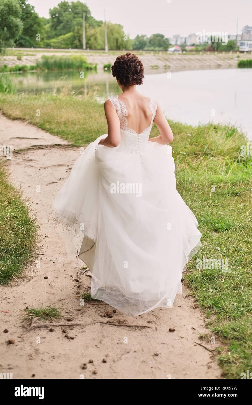 Bride goes through the forest holding a magnificent dress, wedding ...