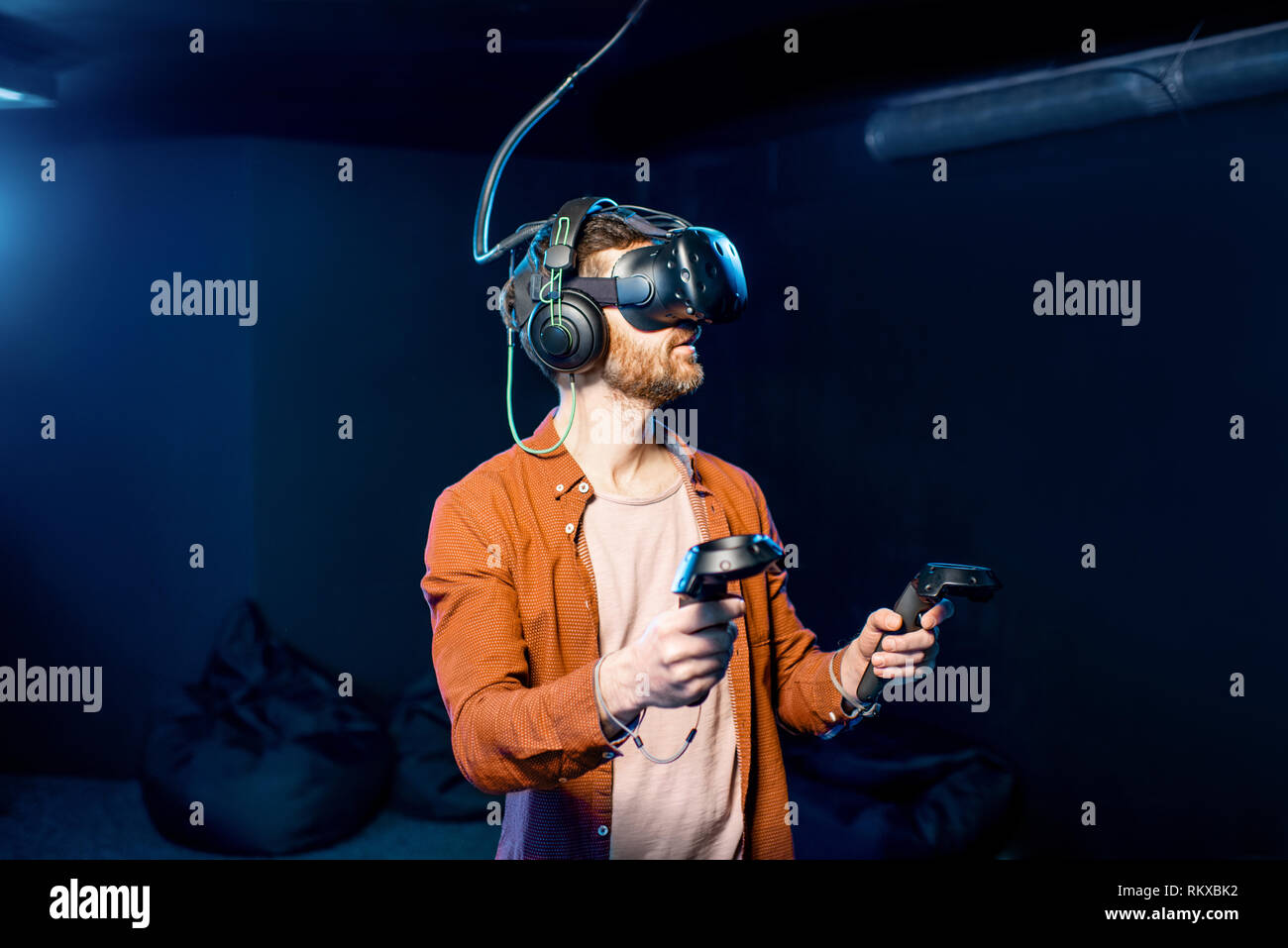 Man playing game using virtual reality headset and gamepads in the dark ...