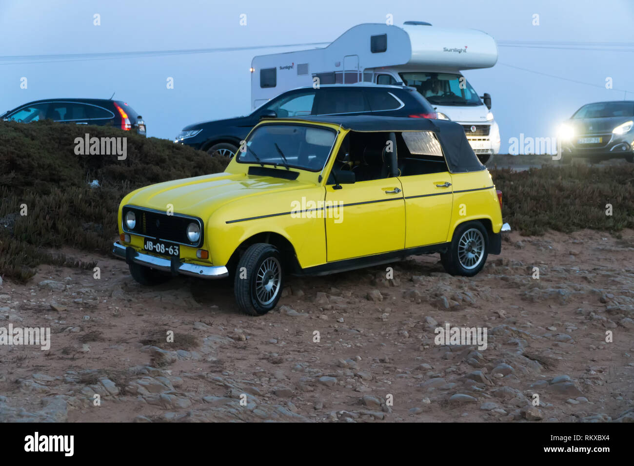 Yellow Renault 4 car oldtimer convertible parked at stony parking by the sea at sunset. CAPE ST. VINCENT, PORTUGAL - SEPTEMBER 5, 2018. Stock Photo