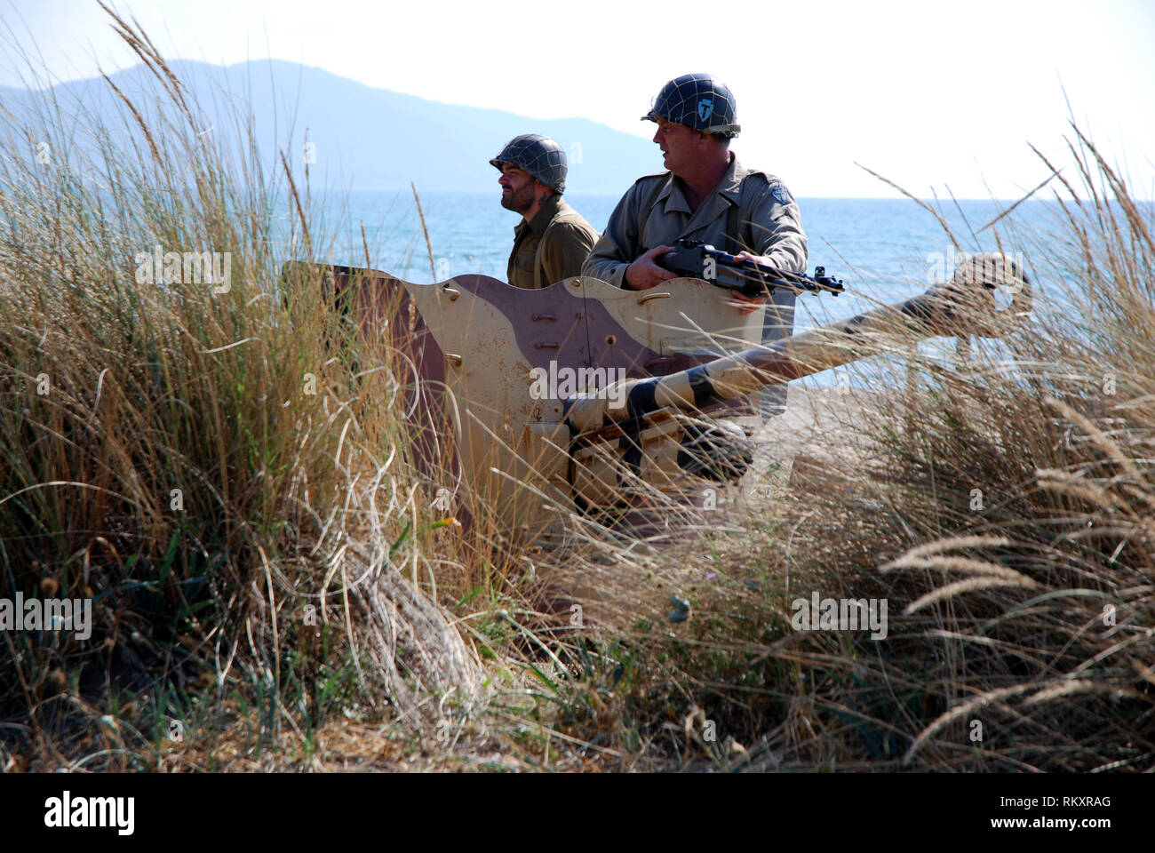 second world war us soldiers near italian anti-tank cannon deployed on the beach of paestum during historical re-enactment of salerno landing 1943 Stock Photo