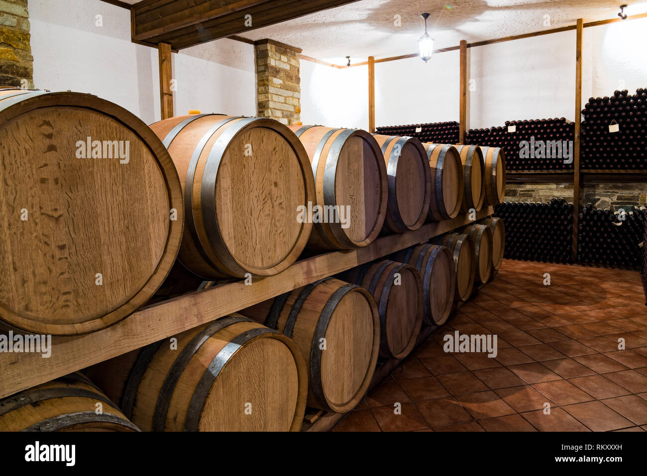 Stacked wine barrels and bottles in the cellar of a winery in Elassona