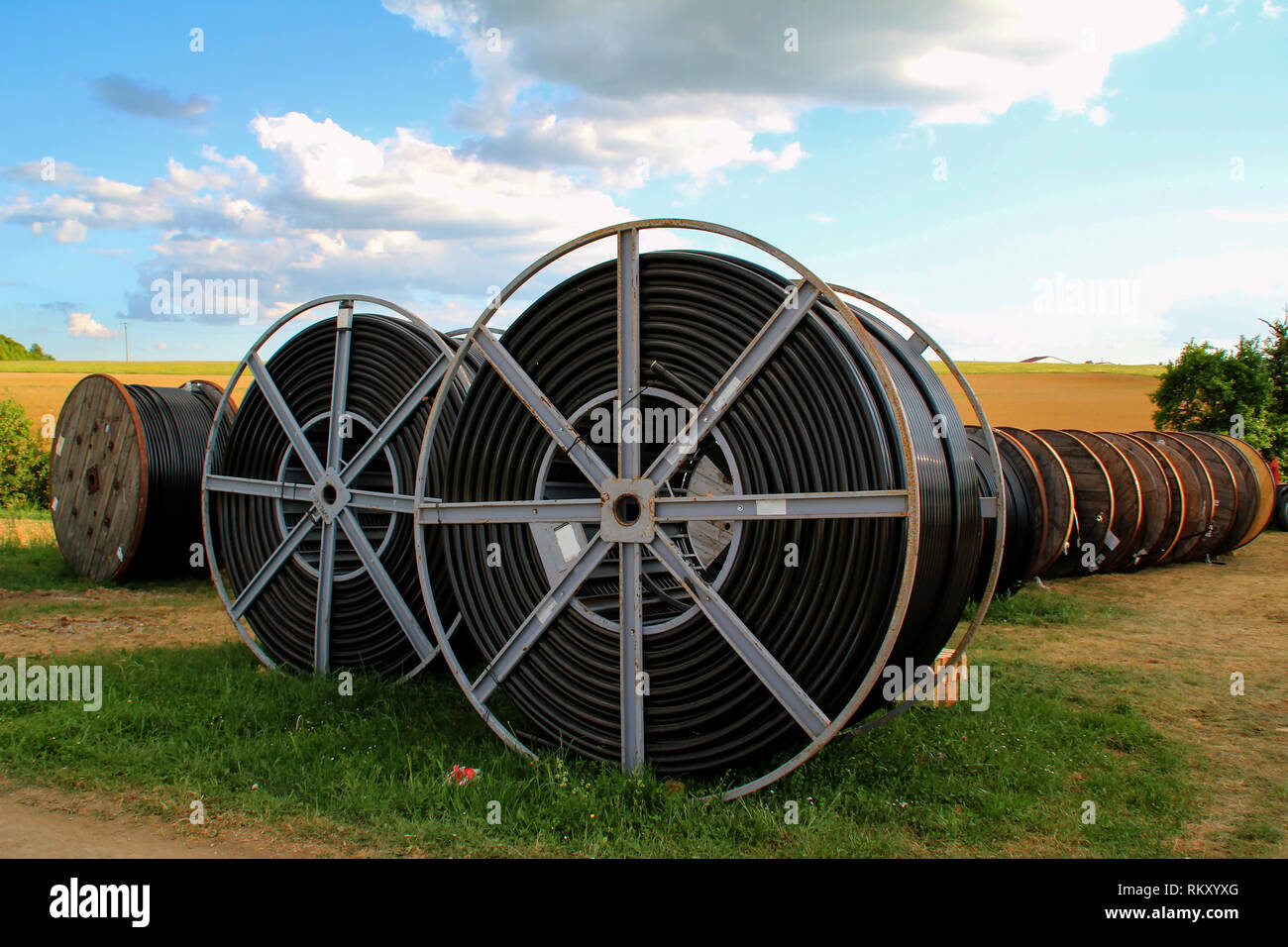 Black wire electric cable with wooden coil of electric cable under the