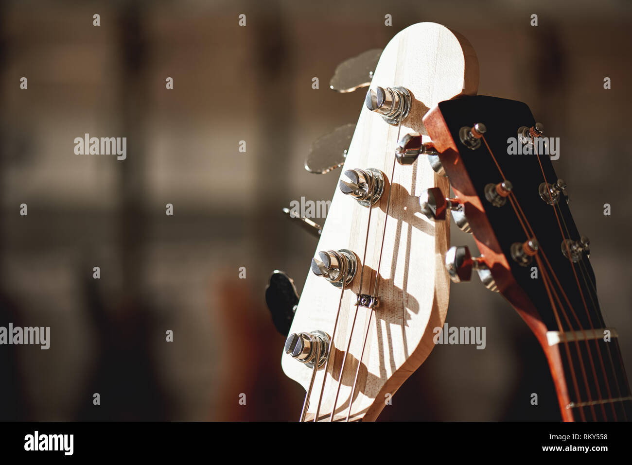 Close-up view of two different guitar headstocks with tuning keys against of a blurred background. Musical instruments. Music store. Guitar body Stock Photo