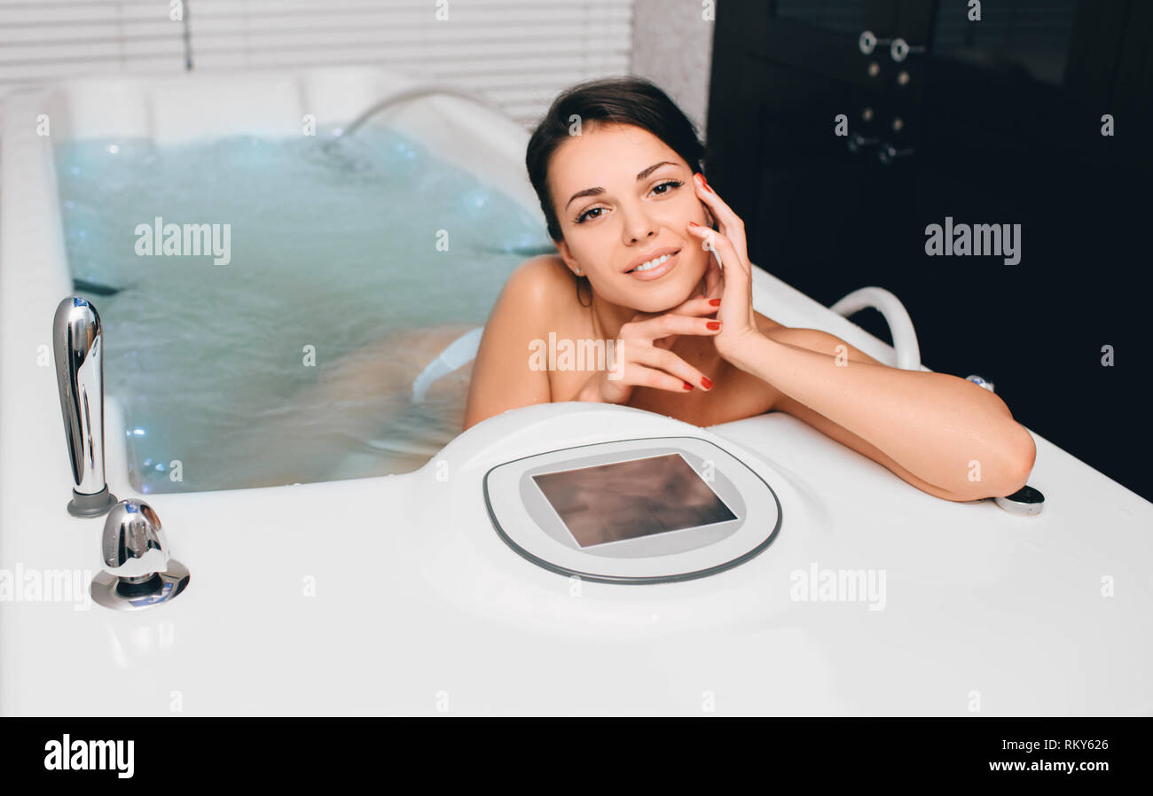 Cute smiling woman relaxing in the bathroom with hydromassage at wellness center Stock Photo