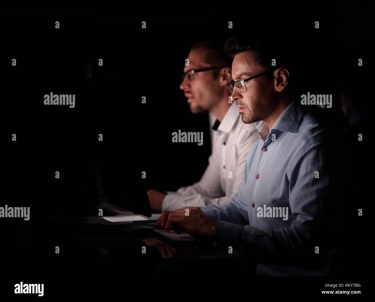 two colleagues sitting at the Desk.isolated on black Stock Photo