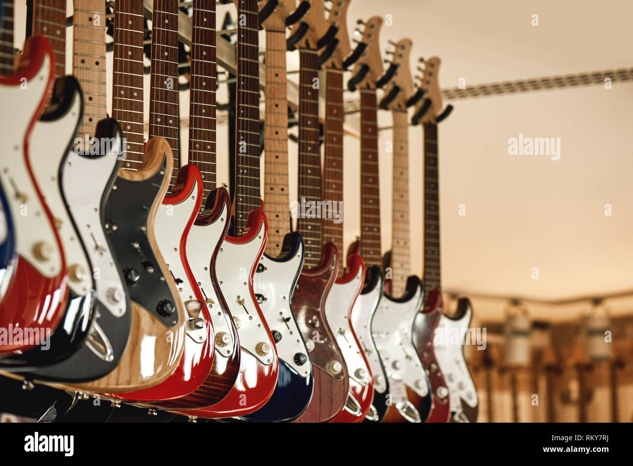 Buying electric guitar. Stand with various colorful electric guitars in