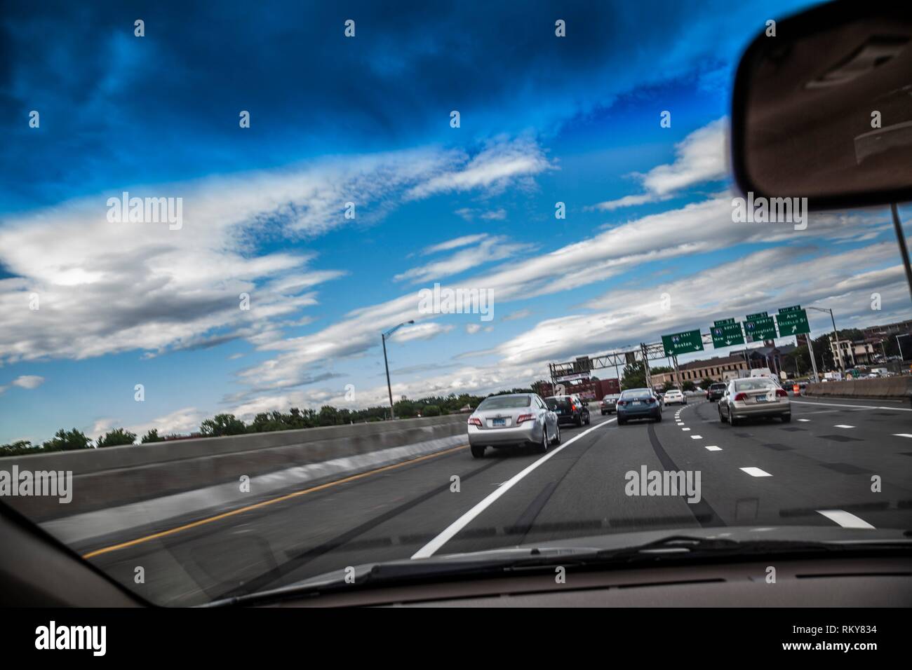 Car driving on a highway with route signs, as seen through its windshield. Stock Photo
