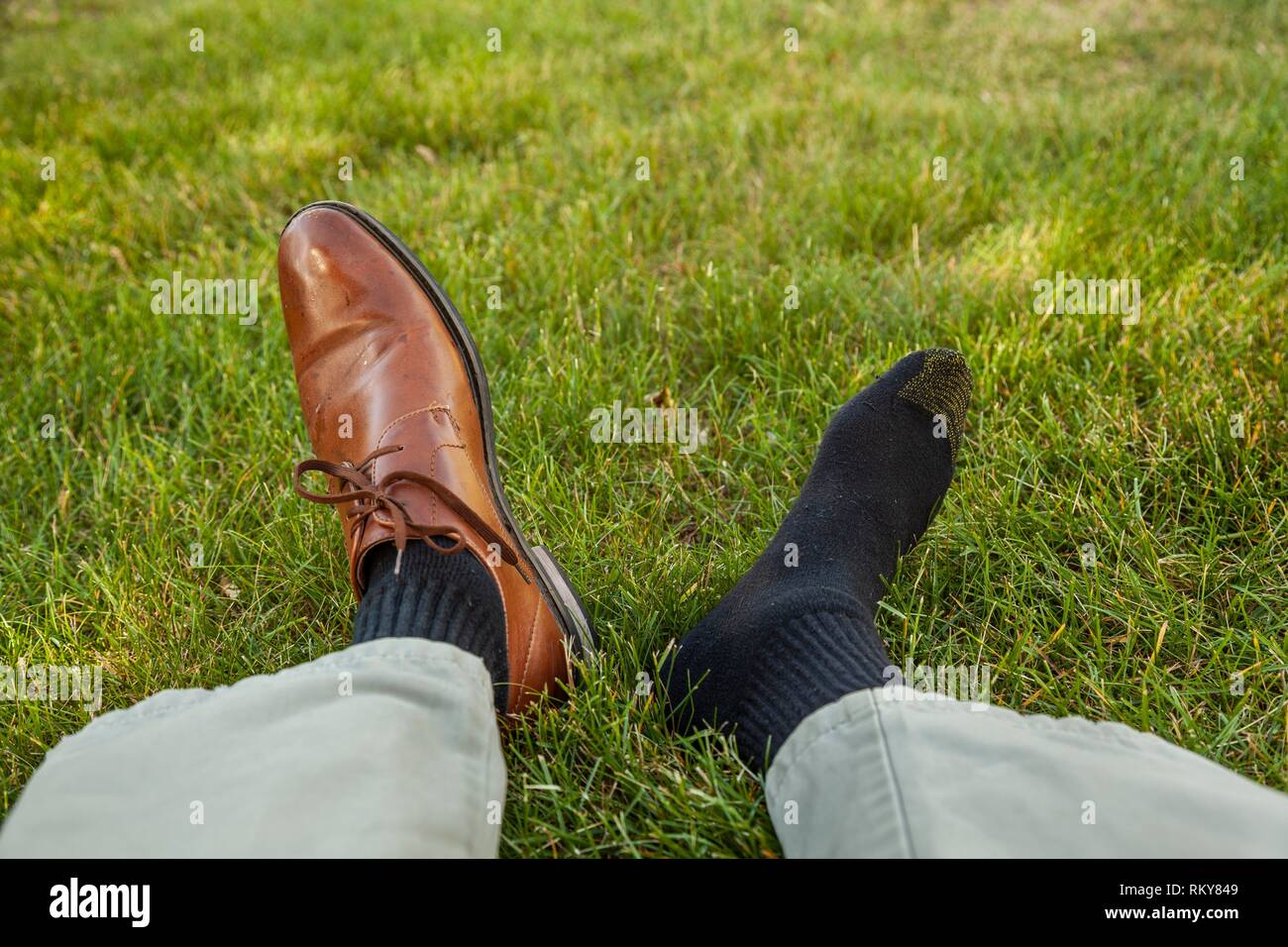 Man's legs and feet - one foot with a shoe and one foot with a sock ...