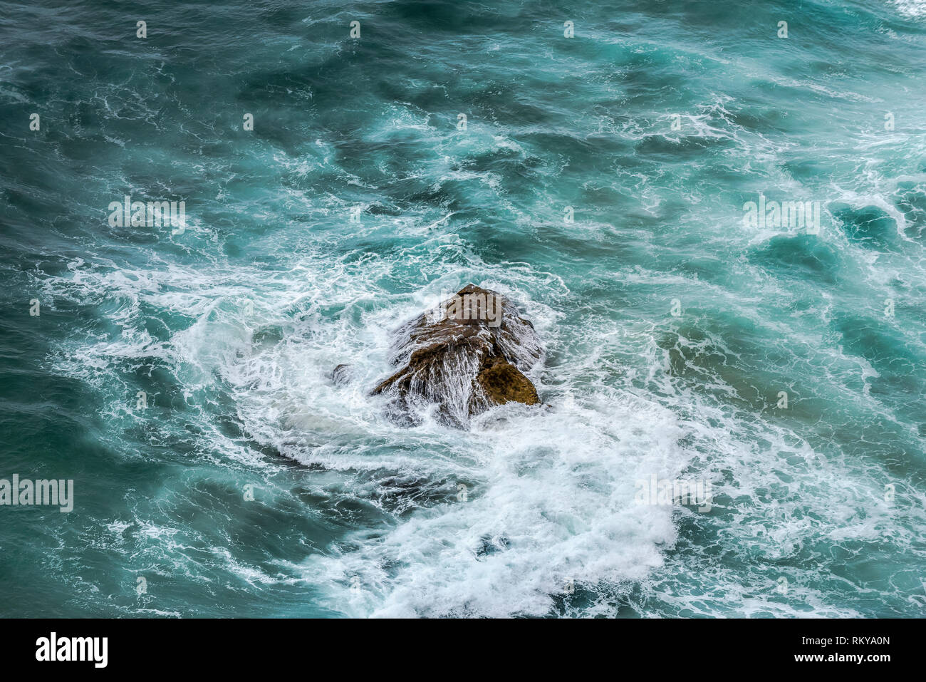 Rough sea swirling around a rock. Stock Photo