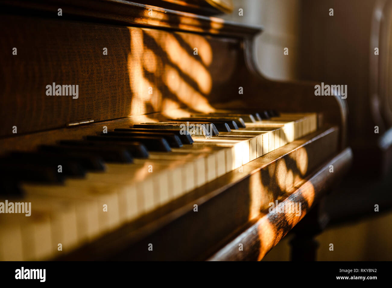 A view across a vintage piano with dappled light. Stock Photo