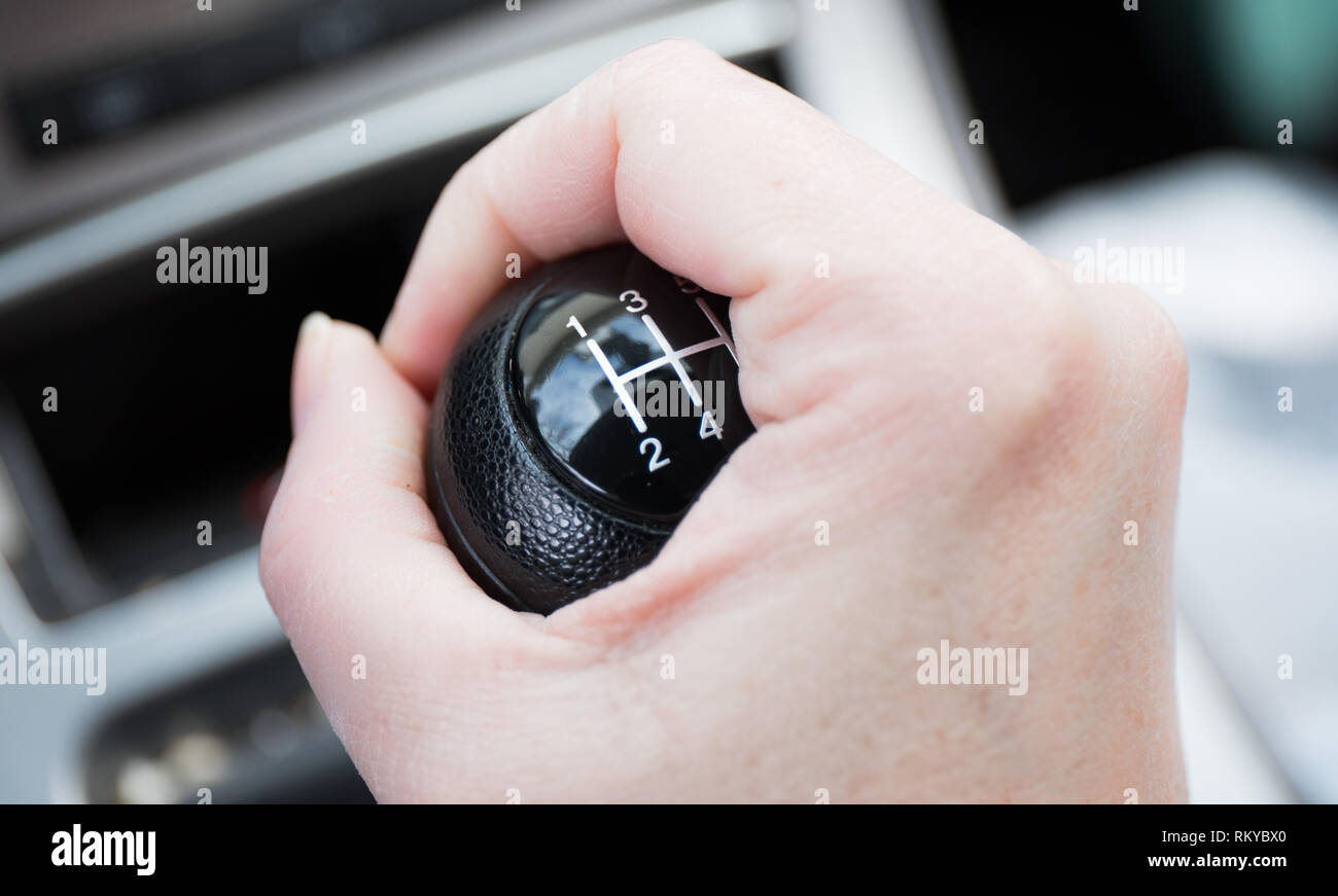 A woman's hand gripping a 5 speed gear shift. Stock Photo