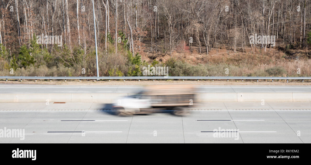 A white cab truck in blurred motion on a highway showing movement while the rest of the shot is in focus. Stock Photo