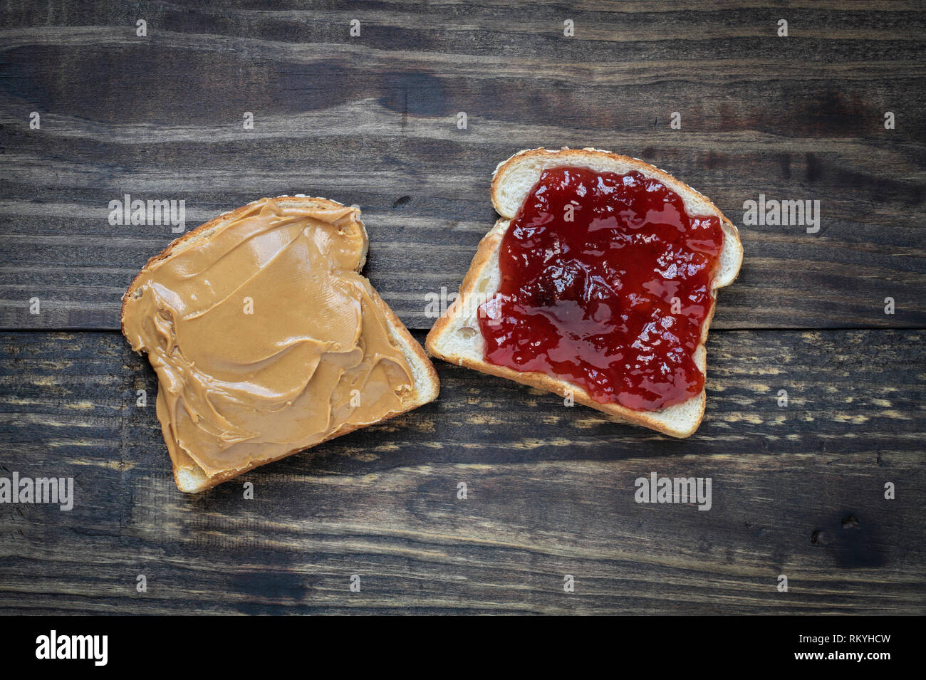 Top view of open face homemade peanut butter and strawberry Jelly sandwich on oat bread, over a rustic wooden background. Stock Photo