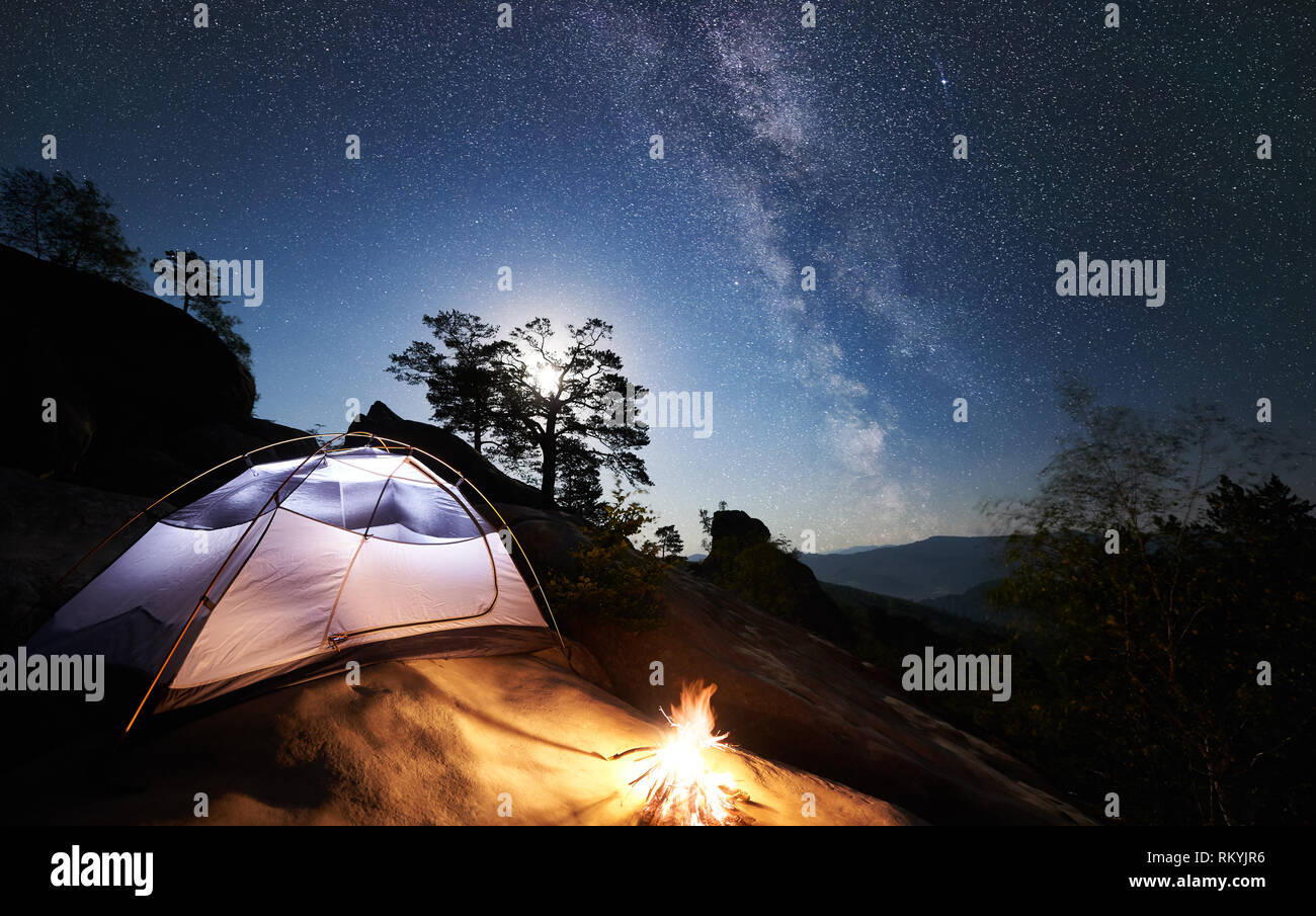 Tourist Camping At Summer Night On Rocky Mountain Glowing Tent And Campfire Under Amazing Night Sky Full Of Stars And Milky Way On The Background Beautiful Starry Sky Big Boulders And Trees Tourist Camping At Summer Night On Rocky Mountain Glowing Tent And Campfire Under Amazing Night Sky Full Of Stars And Milky Way On The Background Beautiful Starry Sky Big Boulders And Trees