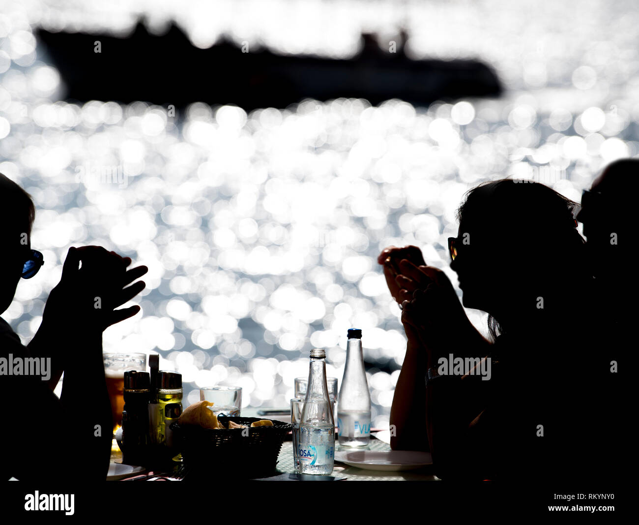 Tourists eating seafood in a seaside restaurant by the Mediterranean Sea. Stock Photo