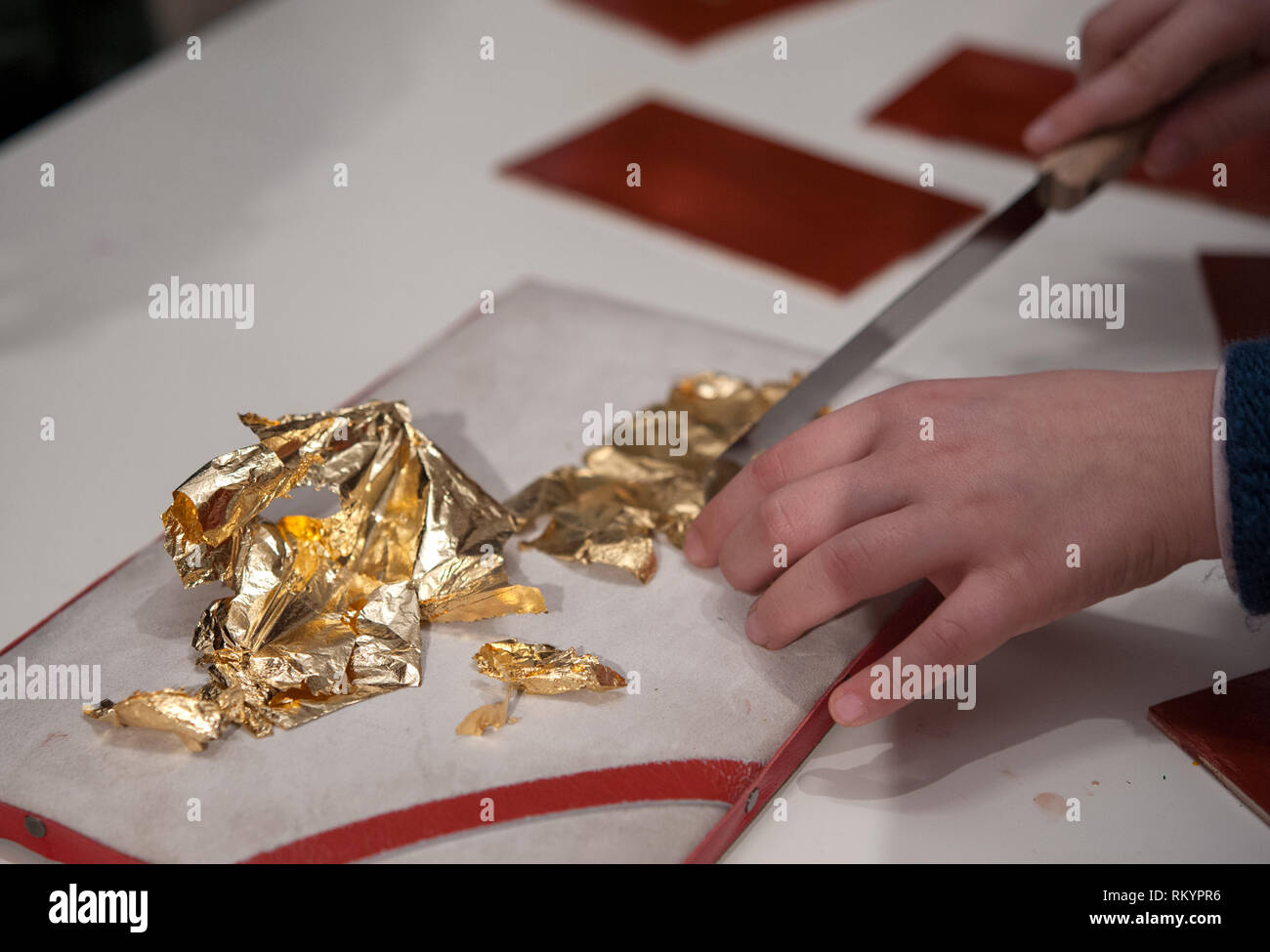 Craftsman cuts an extremely thin gold leaf for the gilding tecnique. Stock Photo