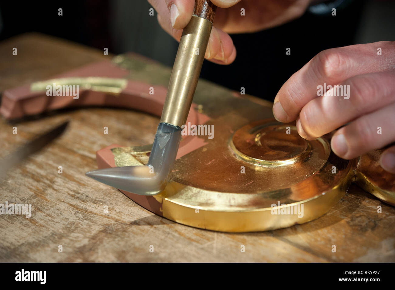 Craftsman uses agate stone for the burnish process. Gilding tecnique. Stock Photo