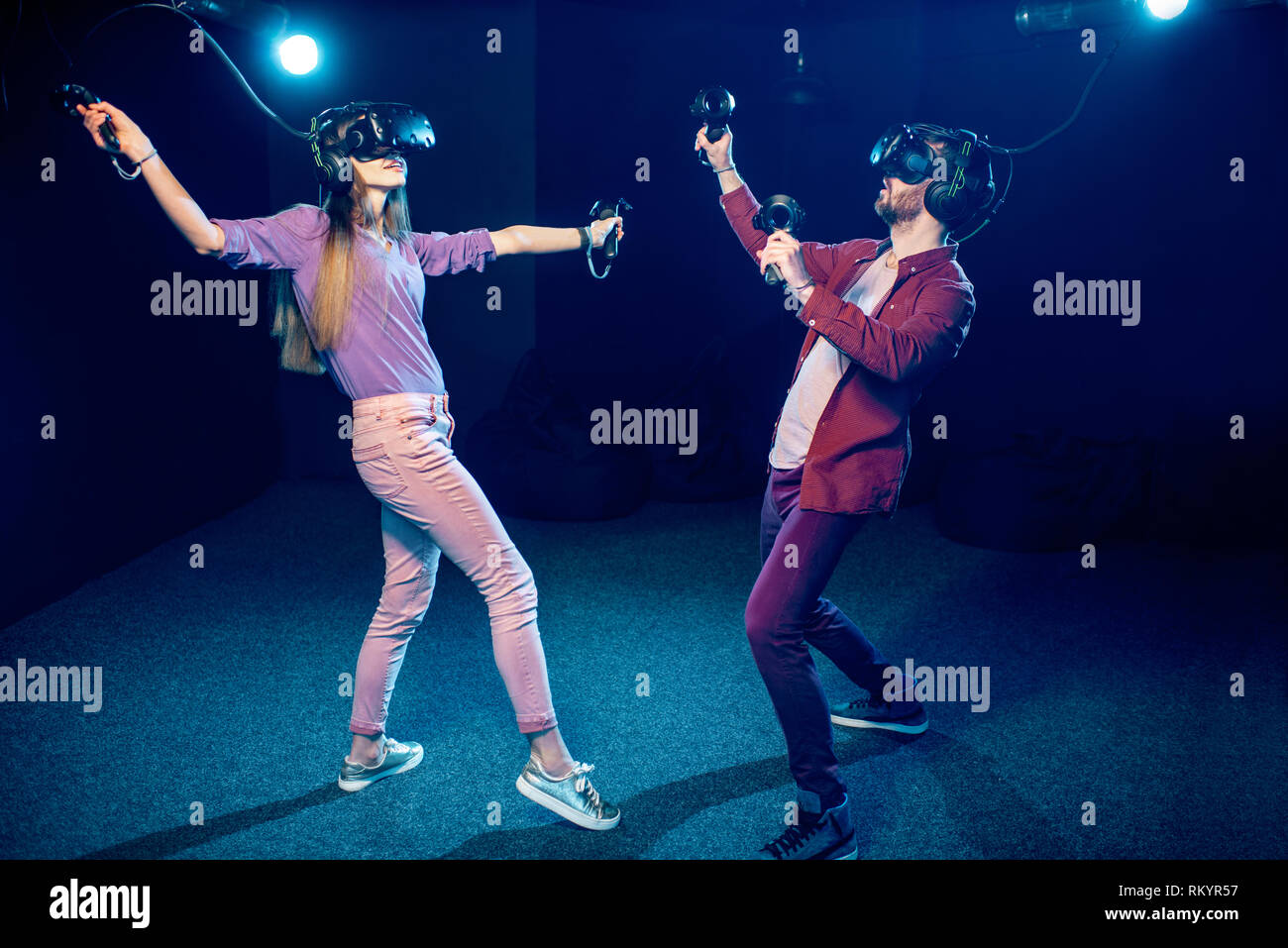 Man and woman playing game using virtual reality headset and gamepads ...