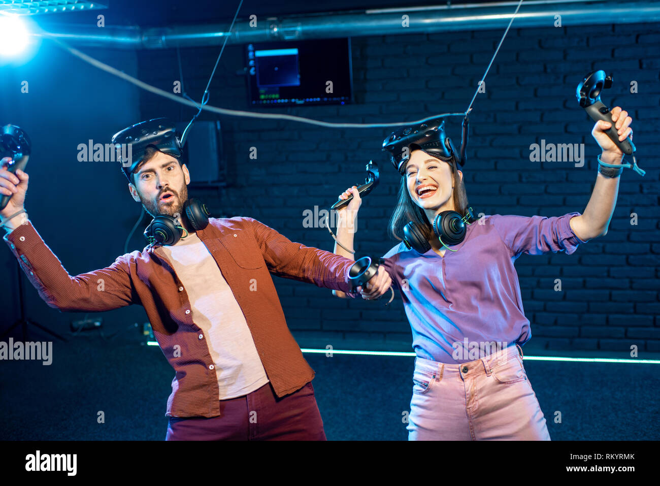 Man and woman simulating weightlessness with virtual reality headset and gamepads in the dark room of the playing club Stock Photo
