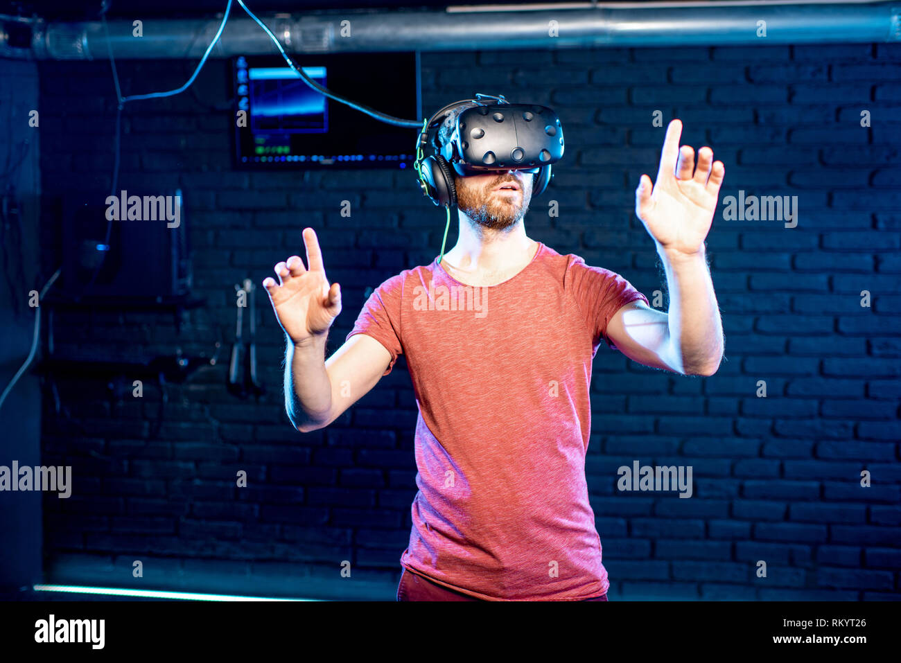 Man touching virtual reality space using VR headset in the playing room Stock Photo