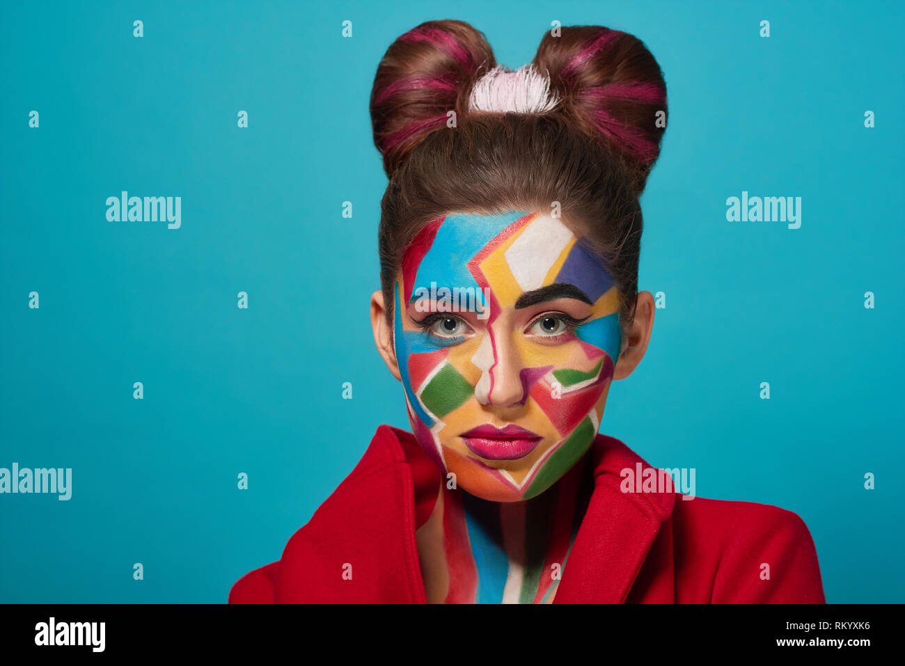 Fashion model looks like comic character, has creative, colorful pop art make up and pink plump lips. Pretty confident woman looking at camera, posing. Stylish bow hairstyle. Stock Photo