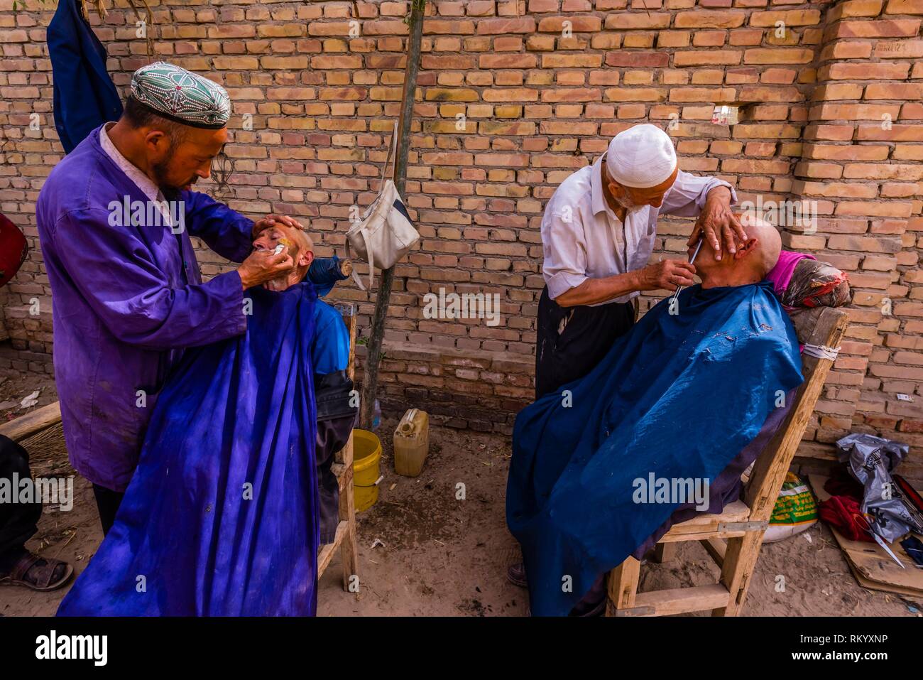 Uyghur men getting a haircut and shave at the weekly market at Opal (Upal), a village along the Karokoram Highway (50 km. southwest of Kashgar) which Stock Photo