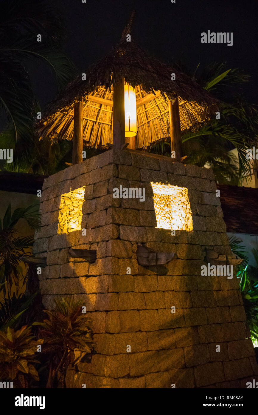 Illuminated stone tower with reed roof at night Stock Photo