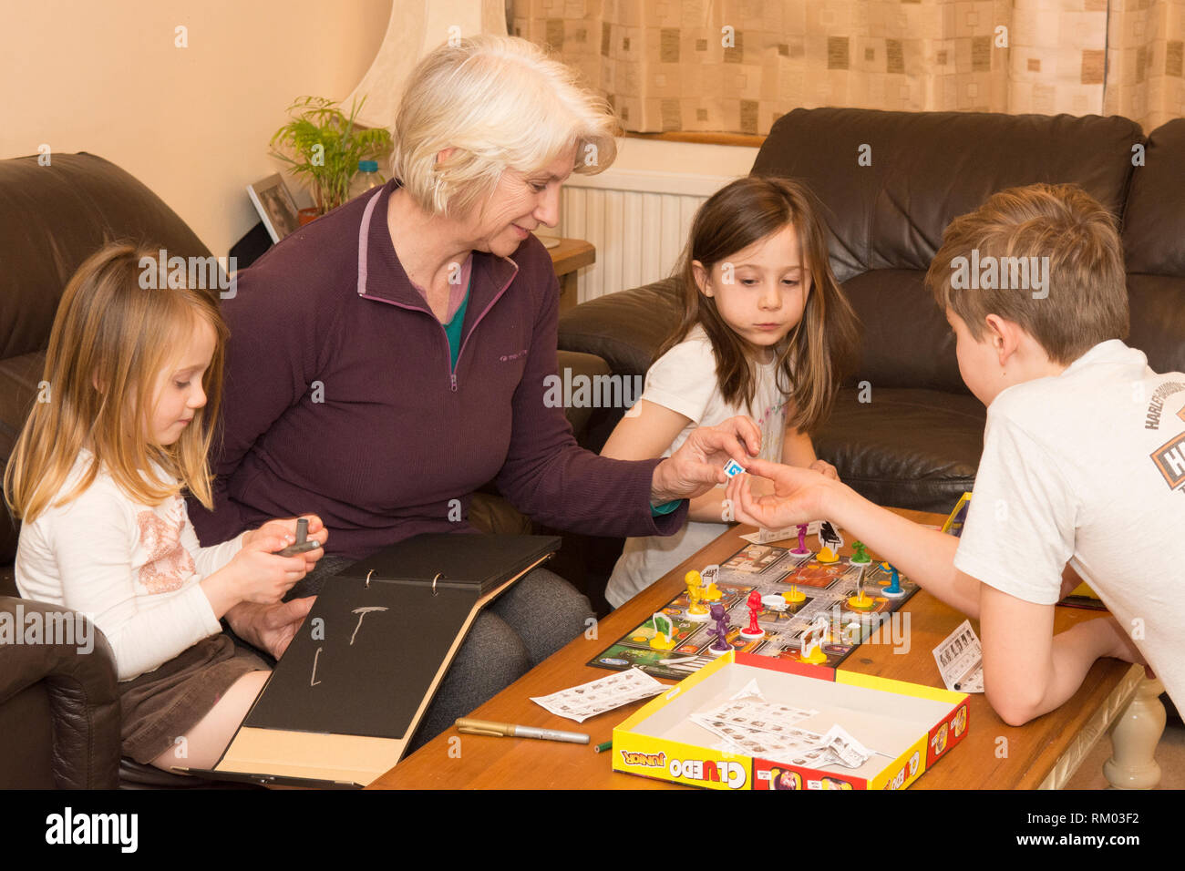 grandmother, granny, playing board game with three grandchildren, aged two to twelve, two girls, one boy. Stock Photo