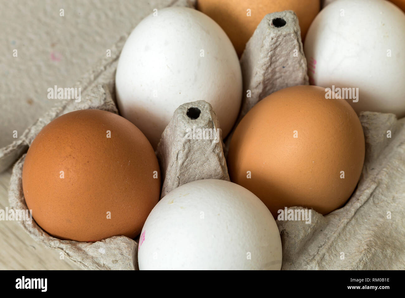 Hen eggs in open cardboard egg carton on kitchen table light copy space