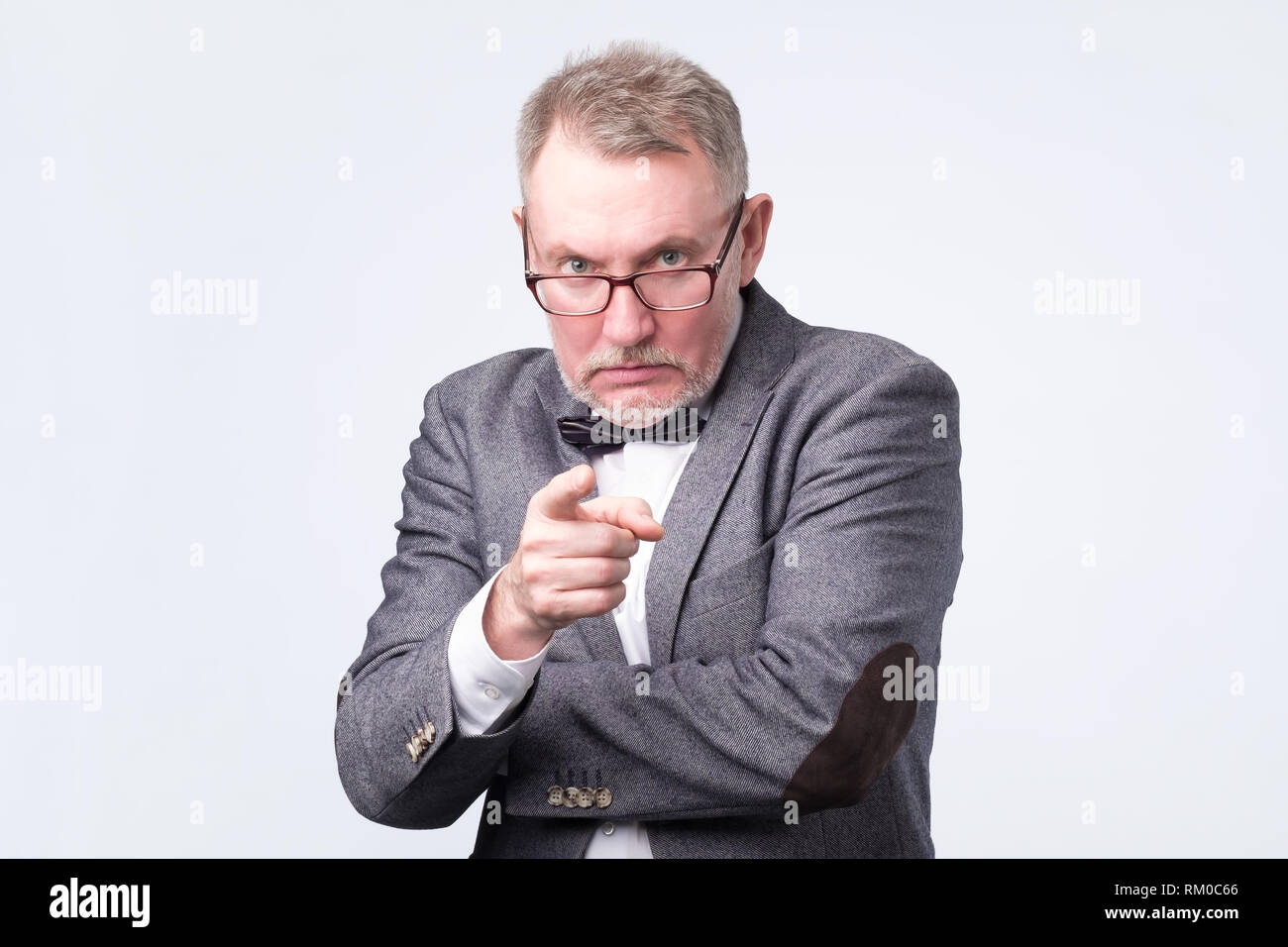 Angry senior man pointing finger at you forcing you to make a choice. Stock Photo