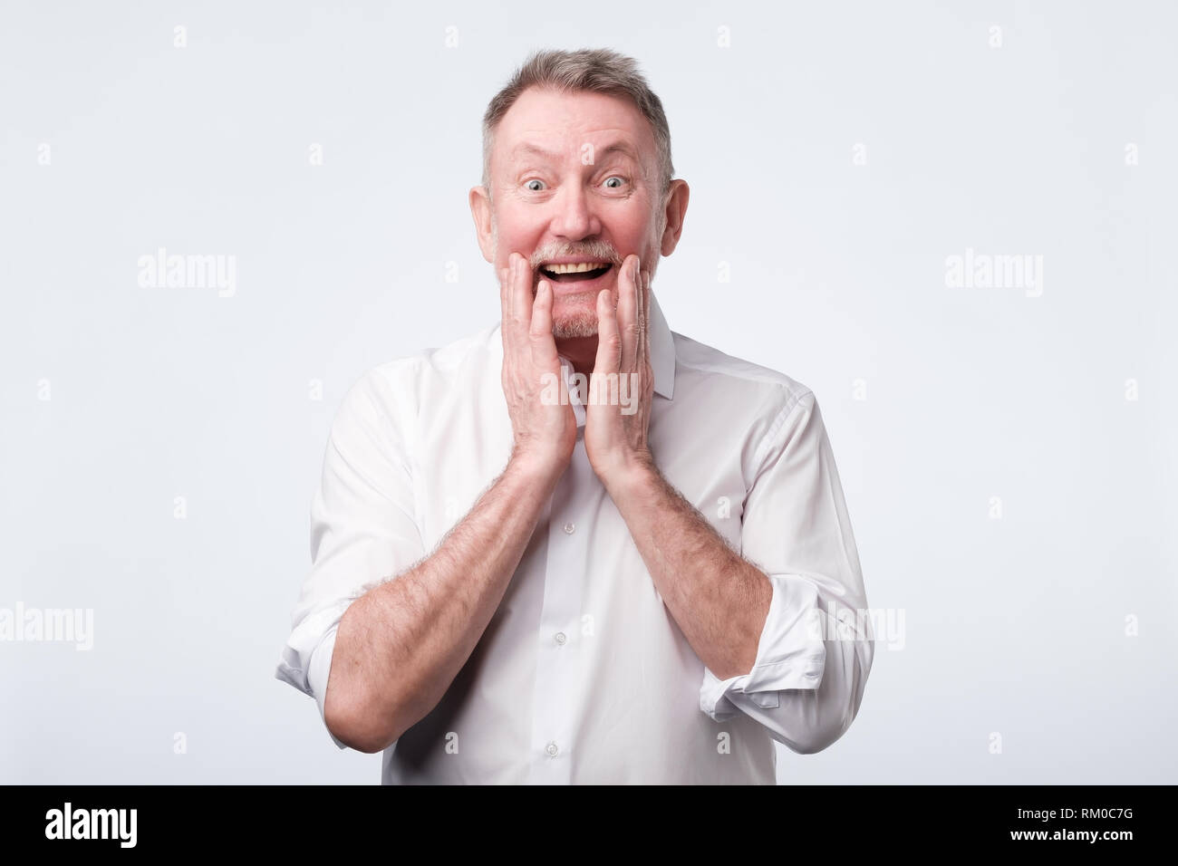 Senior man looks happy glad joyfully widely smiles like heard a good news Stock Photo