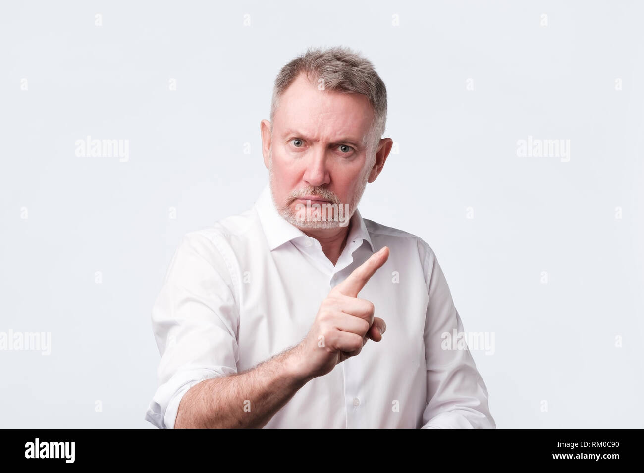 Strict senior man showing index fingers up, giving advice Stock Photo