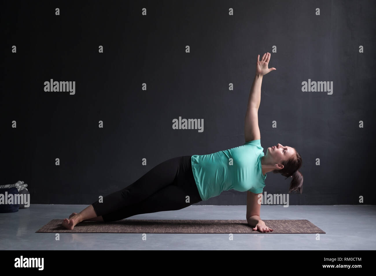 young woman practices yoga asana Vasishthasana or side plank pose Stock Photo