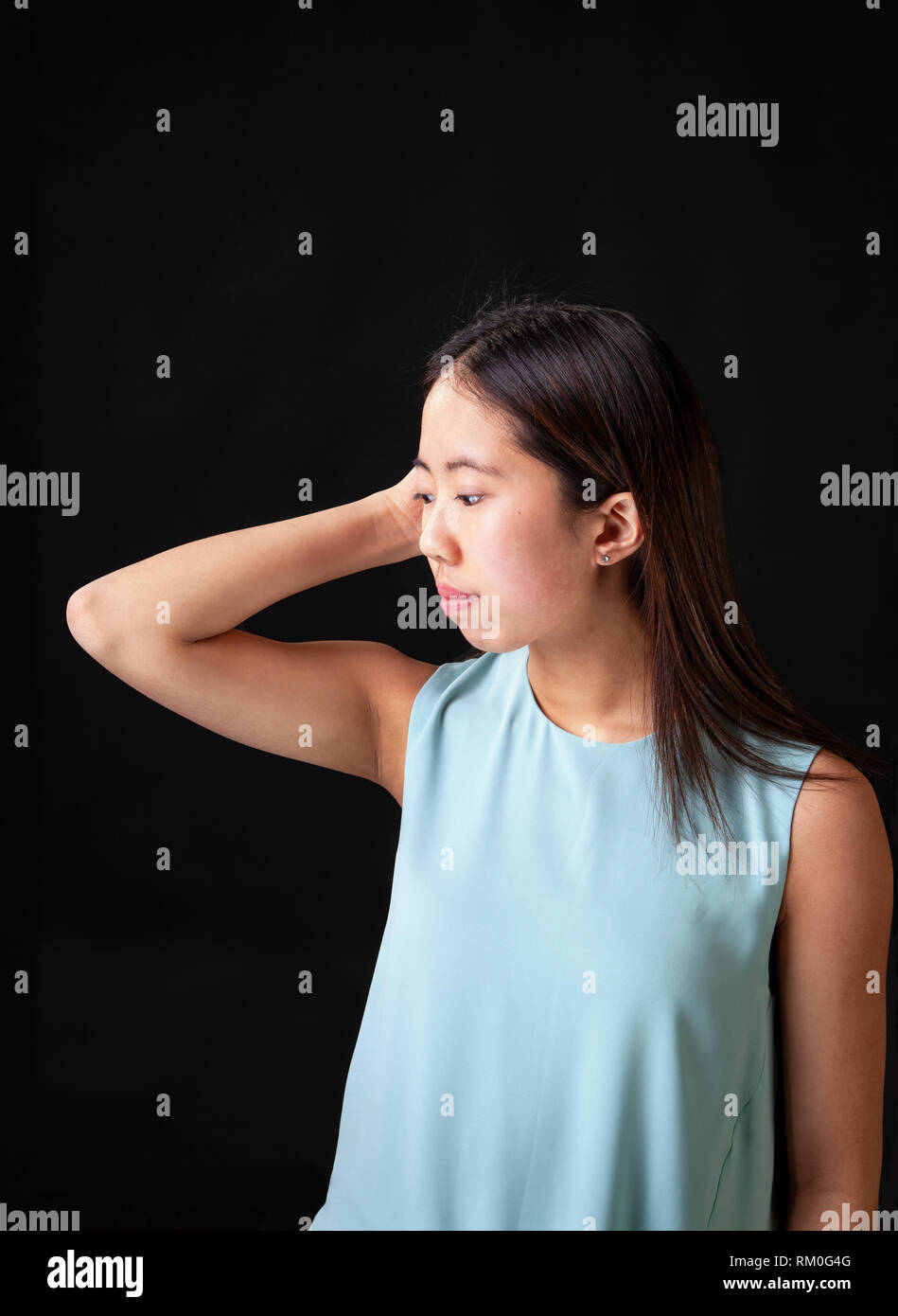 Beautiful young Asian female teen model posing in studio on black background. Stock Photo