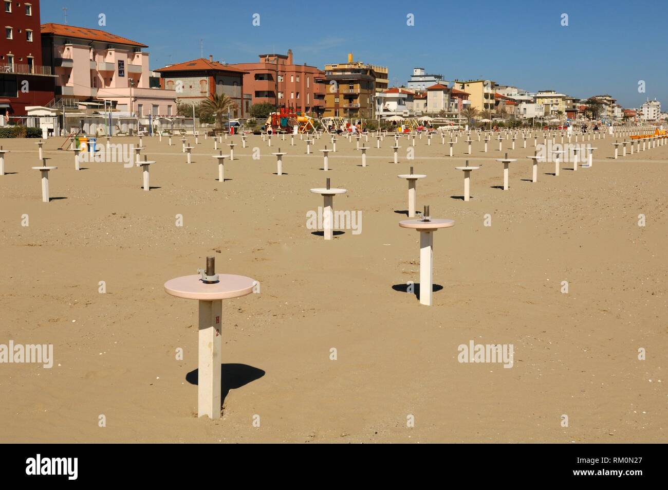 A row of small Poles at Sandy Beach, scenic View at the Beach, Viserbella Beach, Buildings, Hotels of Viserbella, Emilia Romagna, Provence of Rimini, Stock Photo